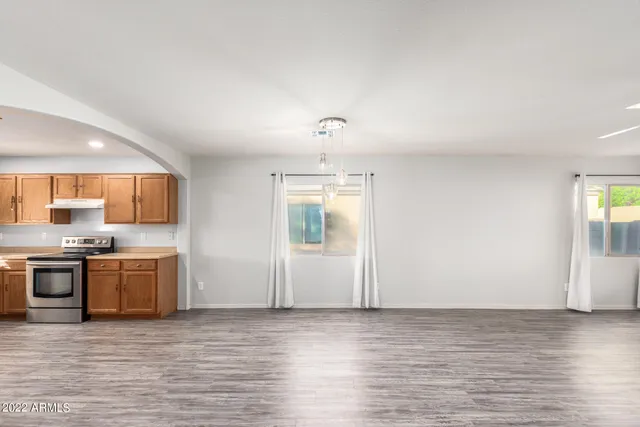 a view of a kitchen with stainless steel appliances granite countertop a stove and a large window