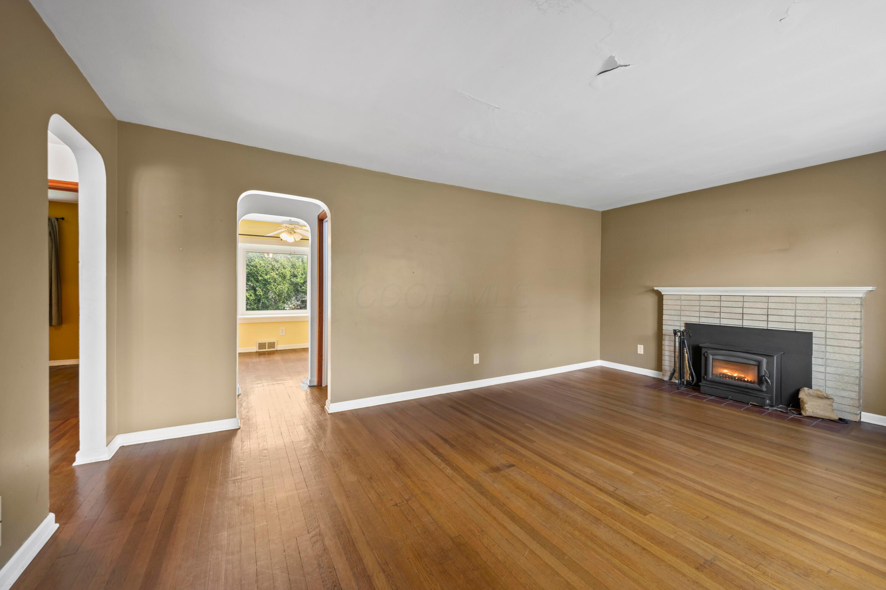 3260 Avalon Road Columbus, OH 43221 - Photo 14 of 46 Hardwood flooring throughout, featuring a fireplace with a white brick surround, and arched doorways
