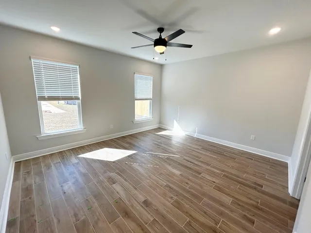 an empty room with wooden floor and windows