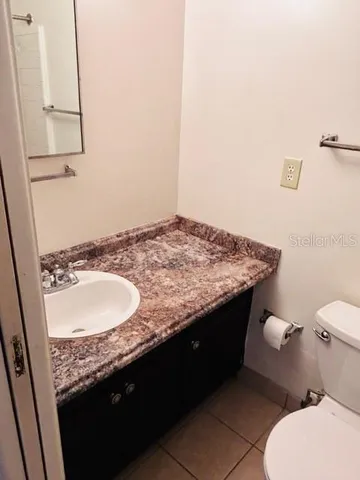 a bathroom with a granite countertop sink and a toilet