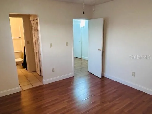 a view of a hallway with wooden floor and a bathroom