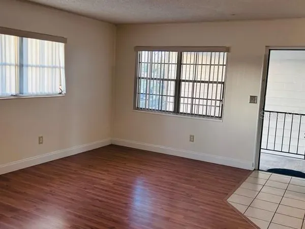 a view of an empty room with wooden floor and a window