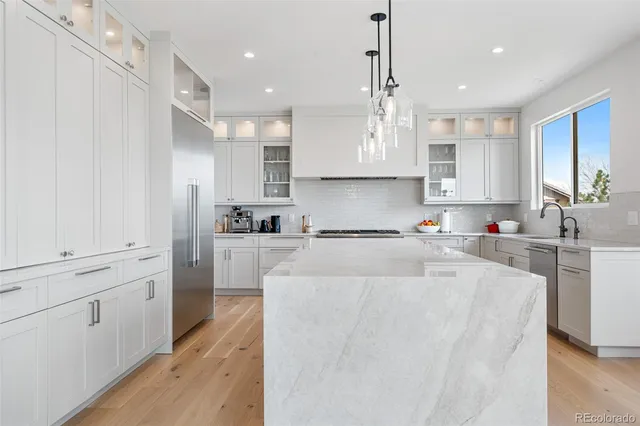 a large white kitchen with lots of counter space a sink appliances and cabinets