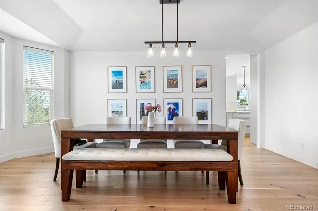 a dining room with wooden floor a chandelier a wooden table and chairs