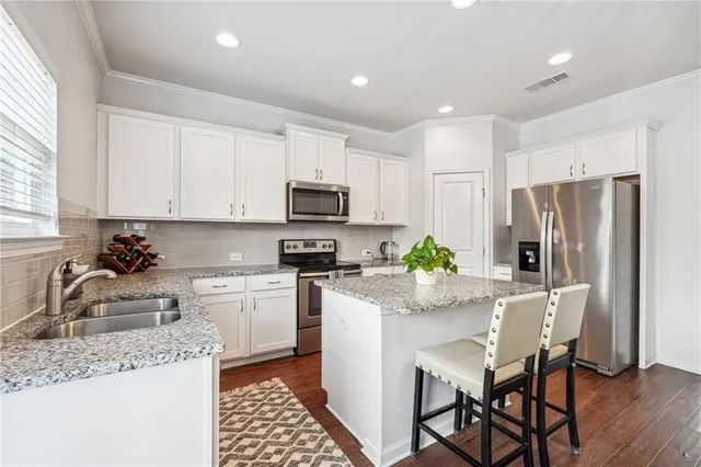 a kitchen with stainless steel appliances granite countertop a refrigerator sink stove microwave and cabinets
