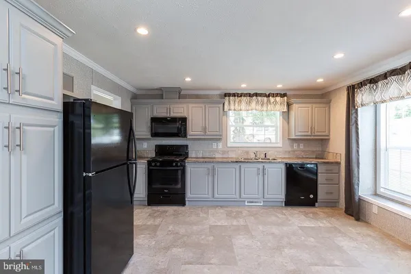 a kitchen with stainless steel appliances granite countertop a refrigerator a sink a stove top oven and a dishwasher next to a window