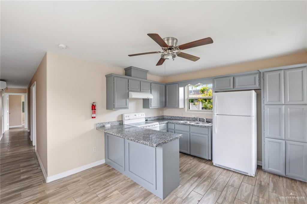 811 Carlson Street Elsa, TX 78538 - Photo 2 of 10 a kitchen with a refrigerator a sink and wooden floor