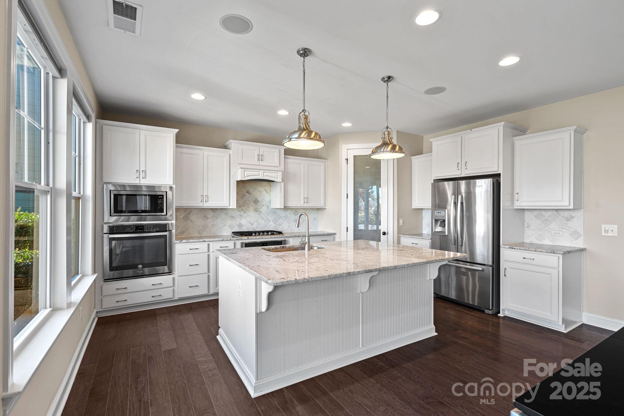 16909 Setter Point Lane Davidson, NC 28036 - Photo 10 of 45 a kitchen with stainless steel appliances a stove a sink dishwasher a refrigerator and white cabinets with wooden floor