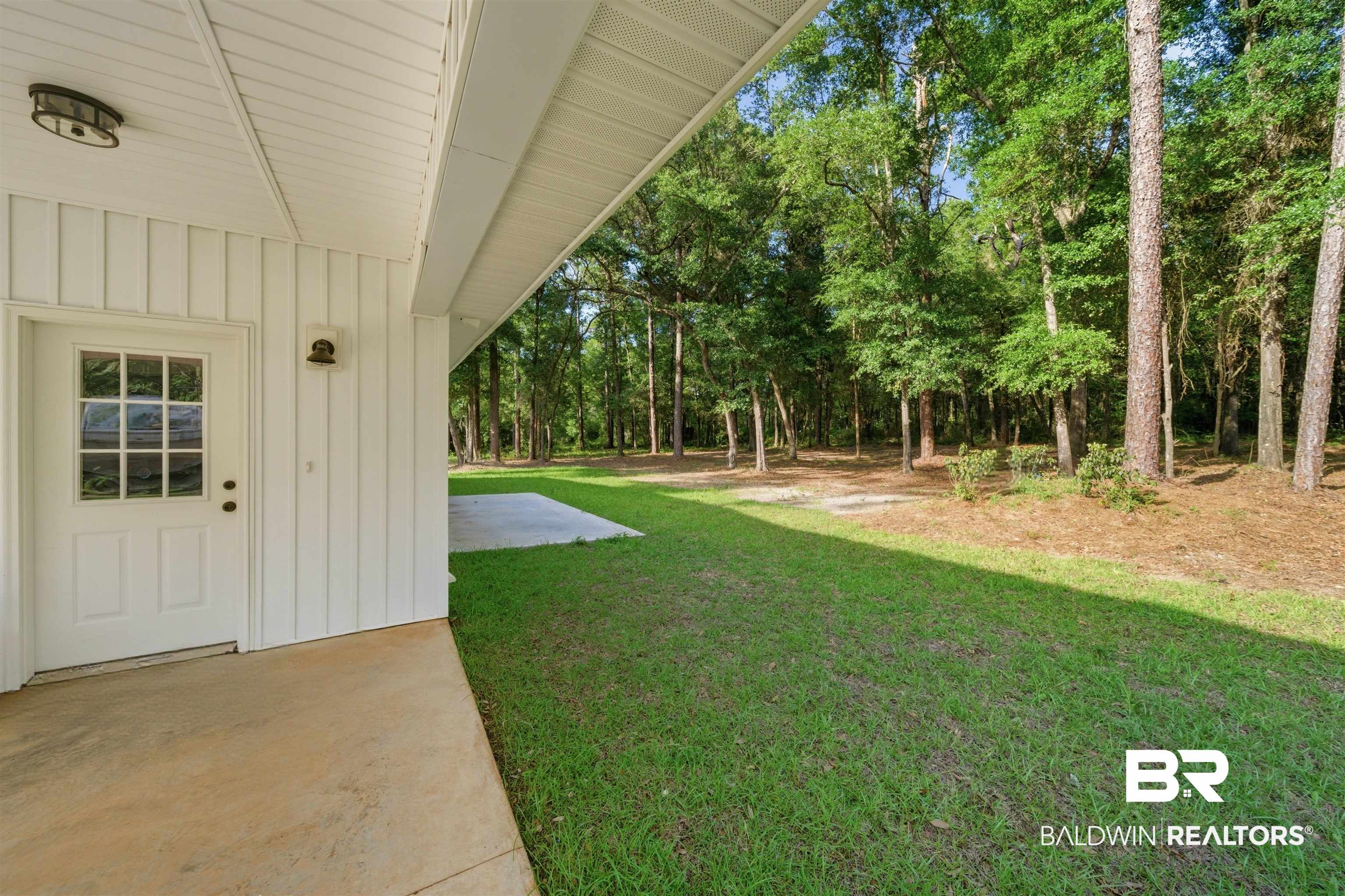 14128 Jackson Lane Foley, AL 36535 - Photo 5 of 36 Covered concrete patio with white board and batten siding, a multi-pane glass door, and a flush-mount outdoor light fixture