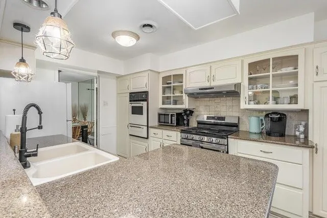 a kitchen with stainless steel appliances kitchen island granite countertop a stove and cabinets