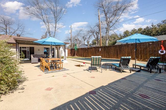 2404 Crestview Circle Irving, TX 75062 - Photo 33 of 39 a view of a patio with table and chairs under an umbrella with barbeque grill and wooden fence