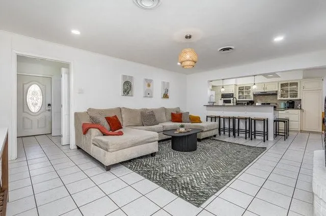 a living room with furniture a rug and kitchen view