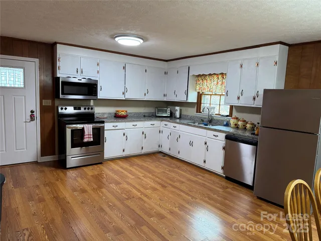 a kitchen with granite countertop a refrigerator stove top oven and sink