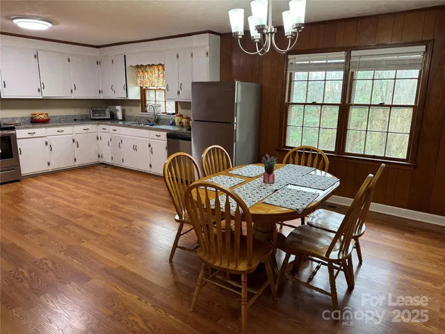 a kitchen with granite countertop a dining table chairs stainless steel appliances and cabinets