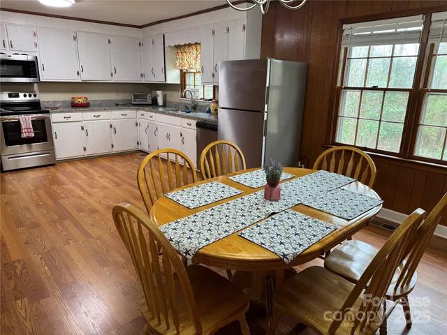 a kitchen with stainless steel appliances granite countertop a stove a sink dishwasher a dining table and chairs with wooden floor