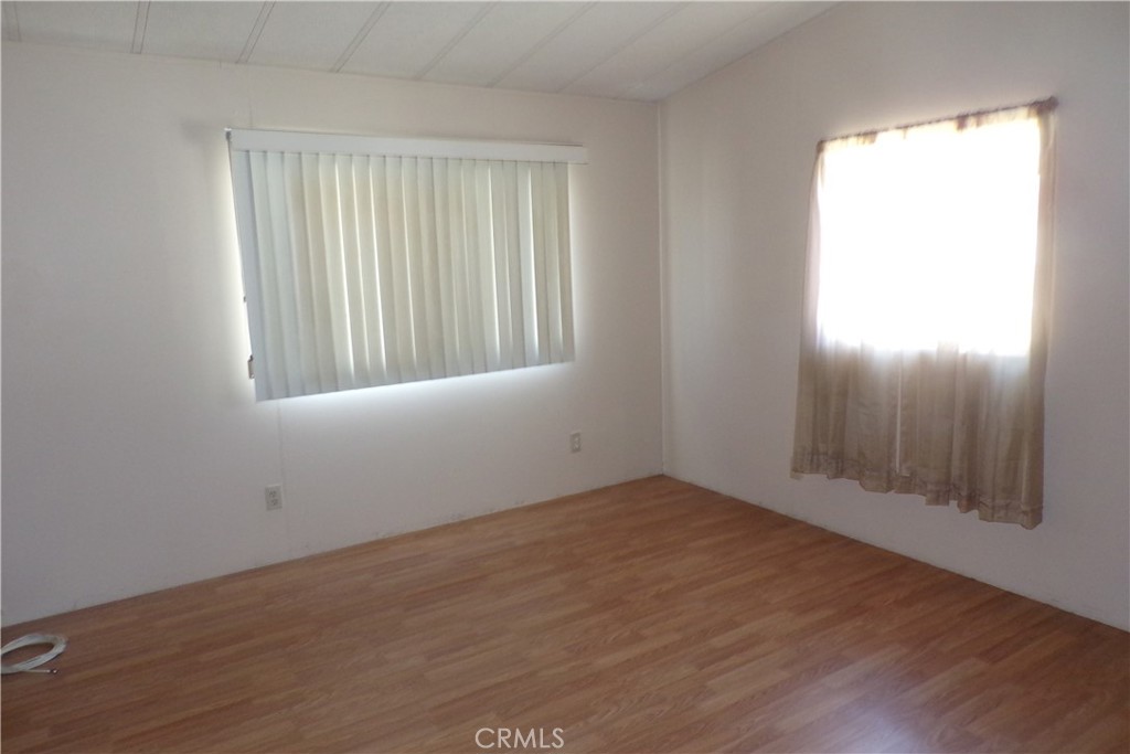34447 Yucaipa Boulevard, Unit 2 Yucaipa, CA 92399 - Photo 13 of 16 an empty room with wooden floor and windows