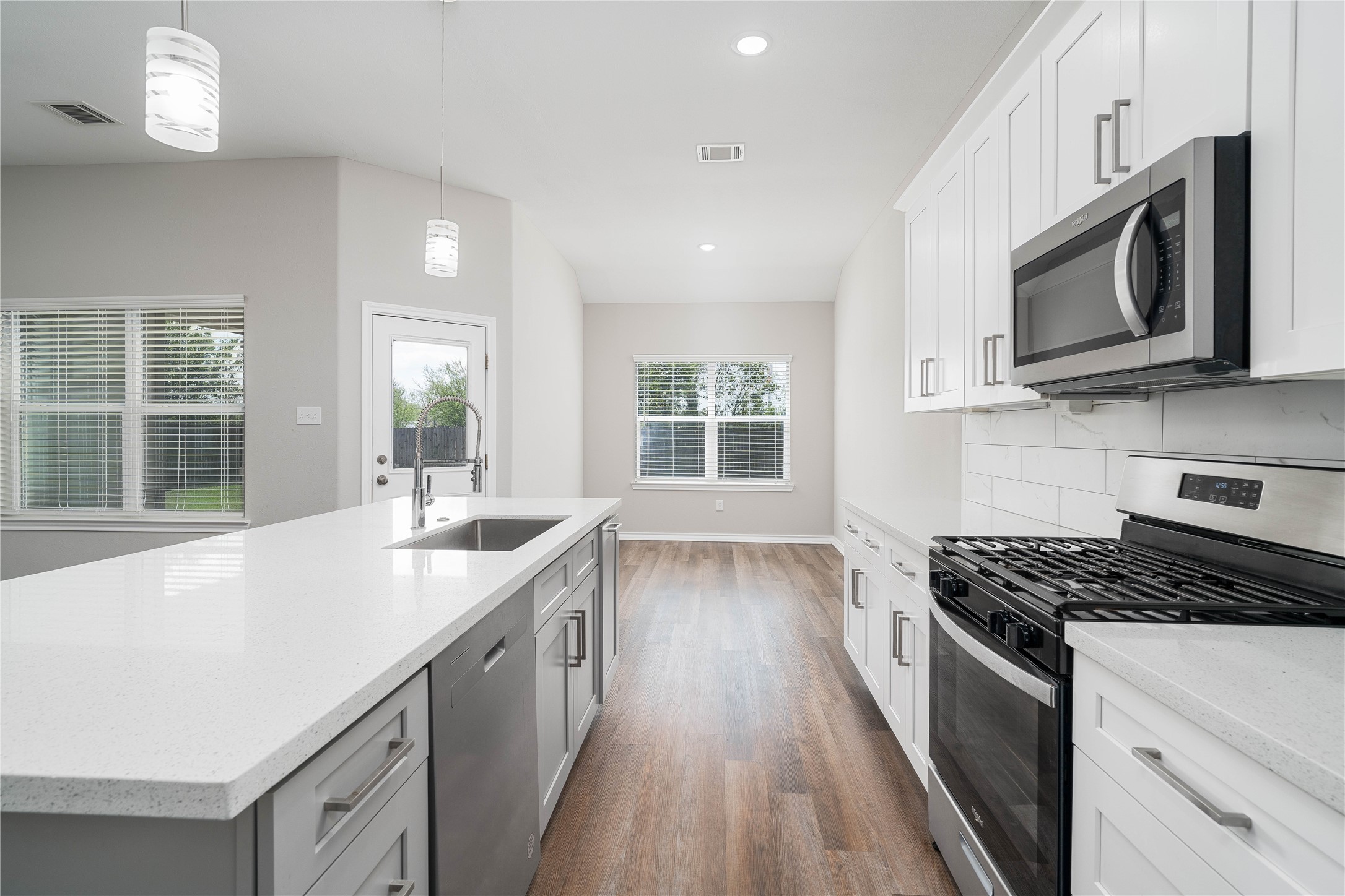 231 McCormick Street Columbus, TX 78934 - Photo 5 of 27 Kitchen & Breakfast Area – Seamless flow from the kitchen to the breakfast area, highlighted by natural light, sleek finishes, and an oversized island with sink and bar seating.