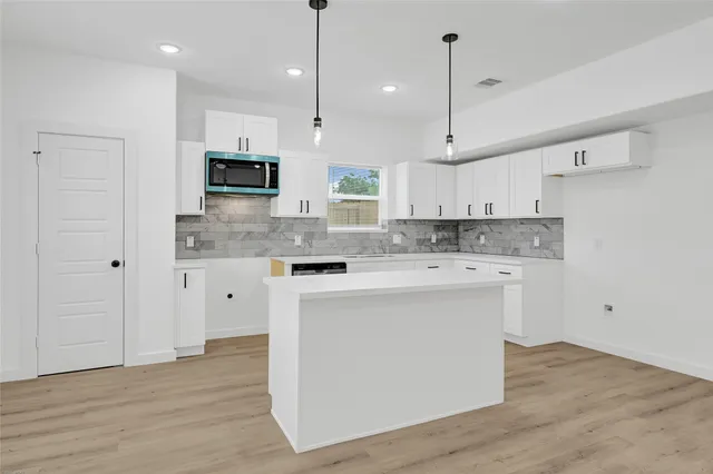 a kitchen with kitchen island a sink stainless steel appliances and white cabinets
