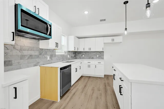 a kitchen with a sink a microwave and cabinets