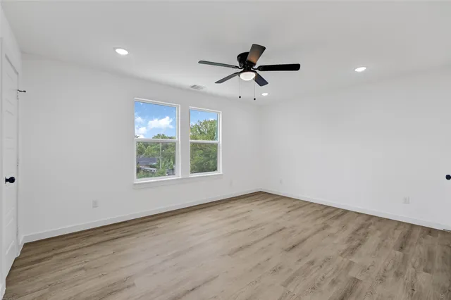 a view of empty room with wooden floor and fan
