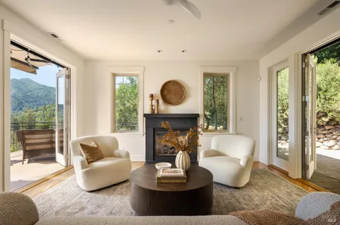 a living room with furniture a fireplace and large windows