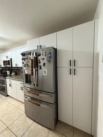 a kitchen with stainless steel appliances a refrigerator and white cabinets