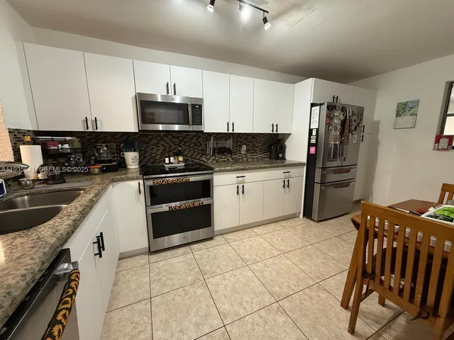 a kitchen with stainless steel appliances granite countertop a stove top oven a sink a counter space and cabinets