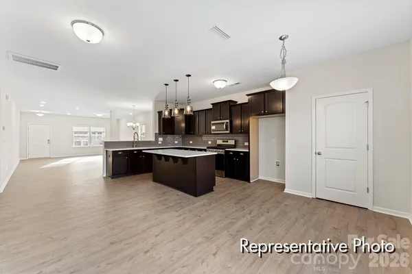 a kitchen with stainless steel appliances kitchen island granite countertop a sink a stove and a wooden floors