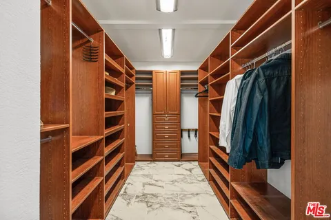 a view of walk in closet with clothes and shoes