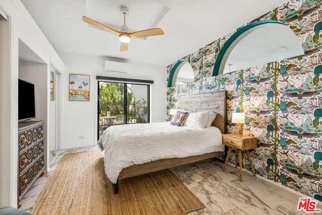 a bedroom with a bed and a flat tv screen on dresser