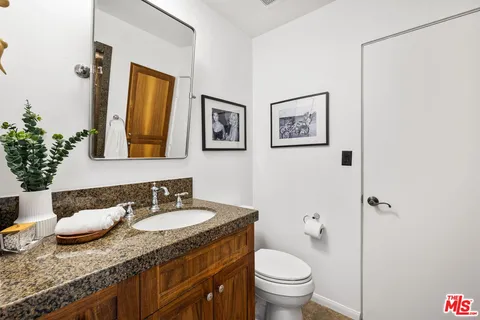 a bathroom with a granite countertop sink toilet and a mirror