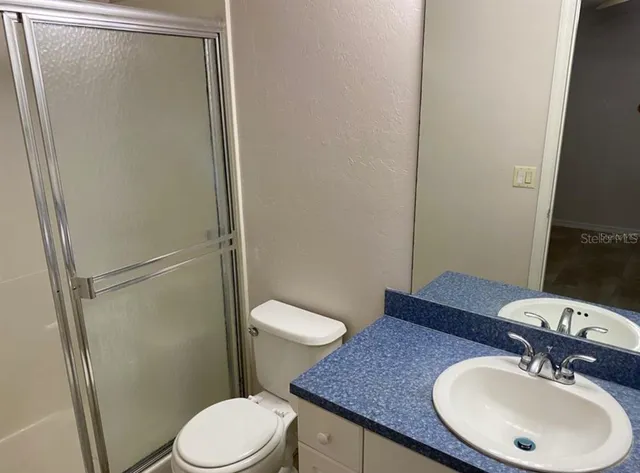a bathroom with a sink a toilet a mirror and shower