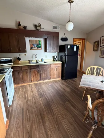 a kitchen with a sink dishwasher a dining table and chairs with wooden floor