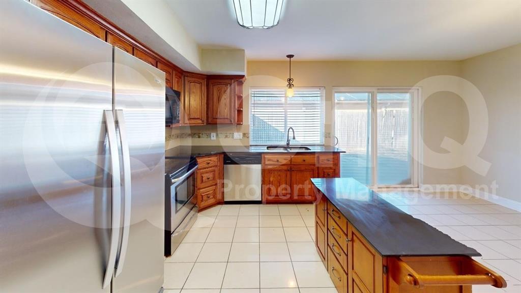 3005 Meandering Way Bedford, TX 76021 - Photo 2 of 24 Kitchen featuring wood cabinetry, stainless steel appliances, dark countertops, and tile flooring