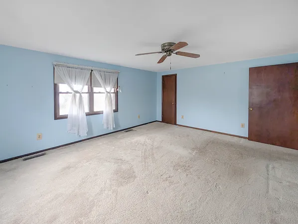 a view of an empty room with a chandelier fan