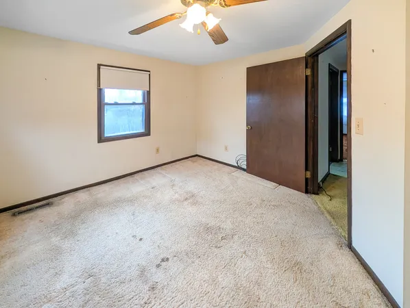 an empty room with a chandelier fan and windows