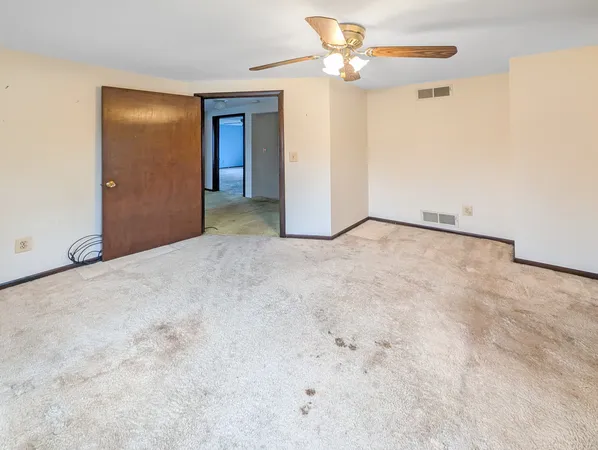 a view of an empty room with chandelier fan