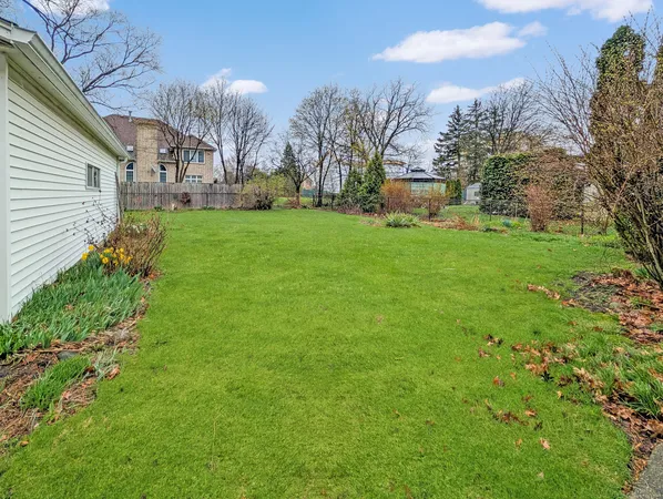 a view of a white house with a yard and a garden