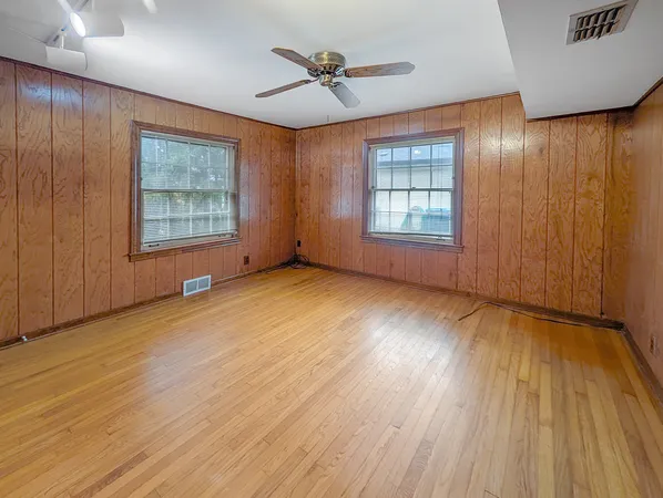 an empty room with wooden floor and windows