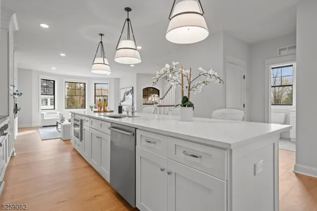 a large kitchen with kitchen island white cabinets and chandelier