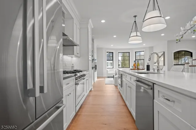 a large kitchen with stainless steel appliances a sink and cabinets