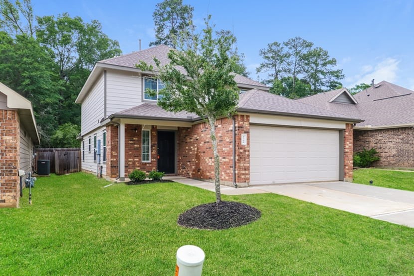 2744 Madison Court Willis, TX 77378 - Photo 2 of 16 a front view of a house with a garden and yard