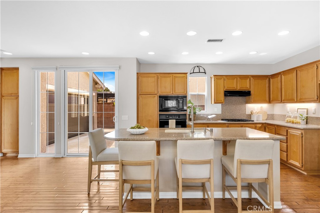 78 Dawnwood Ladera Ranch, CA 92694 - Photo 11 of 54 a kitchen with stainless steel appliances granite countertop a stove top oven a sink dishwasher a dining table and chairs with wooden floor