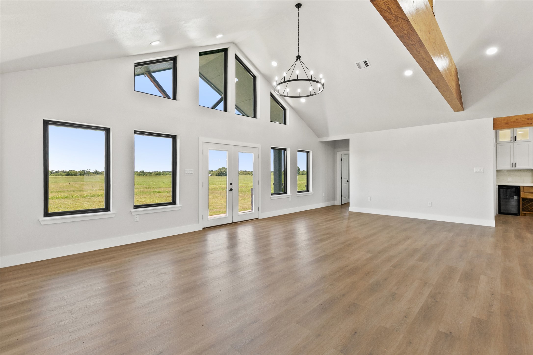 619 Chuckwagon Trail Angleton, TX 77515 - Photo 18 of 37 Large windows extending to the peak of the vaulted ceiling draw in abundant natural light and showcase the wide-open views beyond. French doors provide easy access to the backyard and outdoor living space.