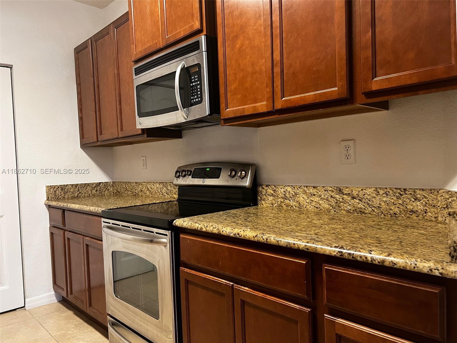 608 Northeast 33rd Terrace, Unit 608 Homestead, FL 33033 - Photo 2 of 35 a kitchen with granite countertop cabinets stove top oven and microwave