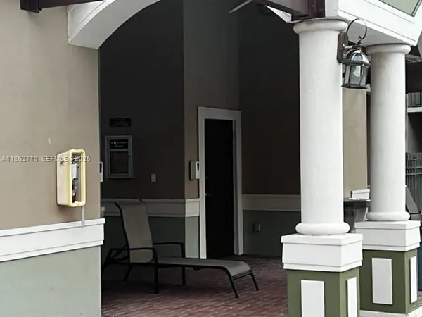 a view of sign board with flower plants and palm tree