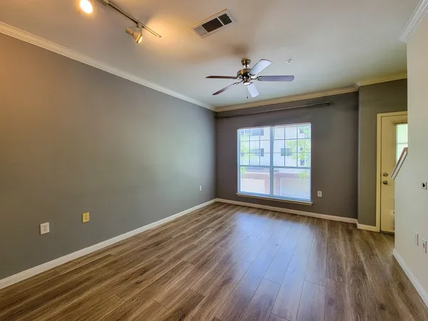 an empty room with wooden floor and windows