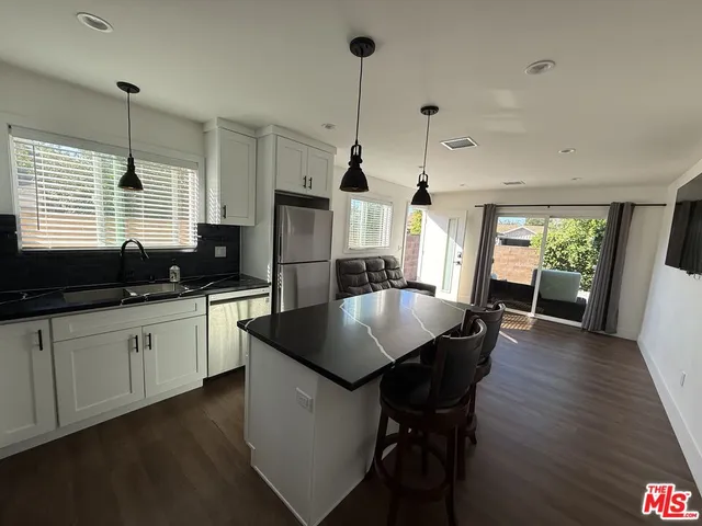a kitchen with granite countertop a sink a counter space appliances and cabinets