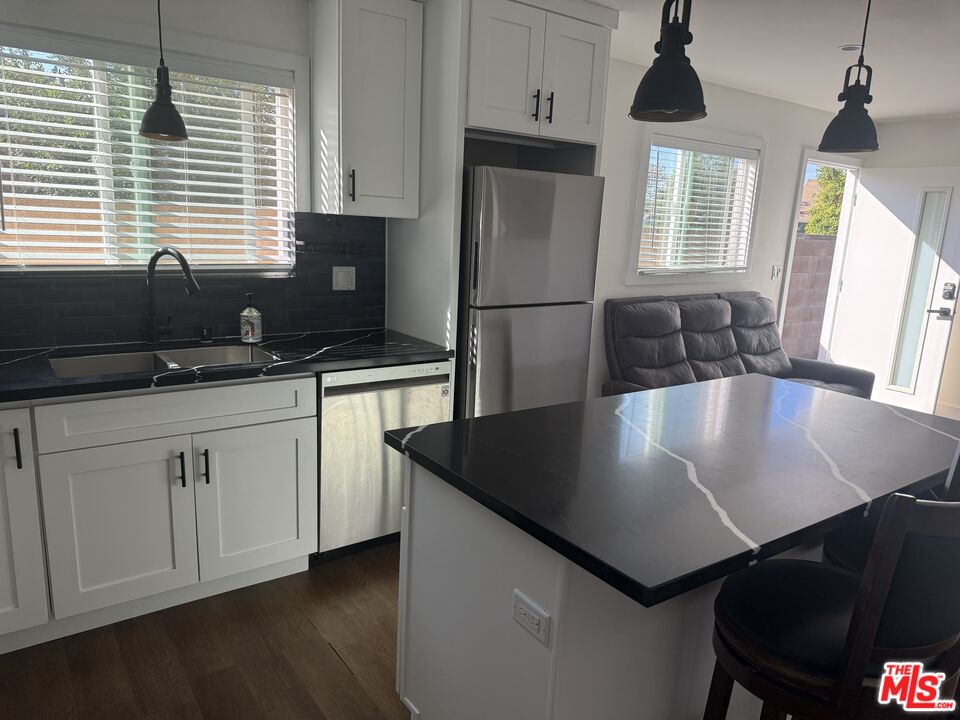 8302 Capps Avenue Northridge, CA 91324 - Photo 3 of 16 a kitchen with stainless steel appliances granite countertop a sink a stove a refrigerator a dining table and chairs