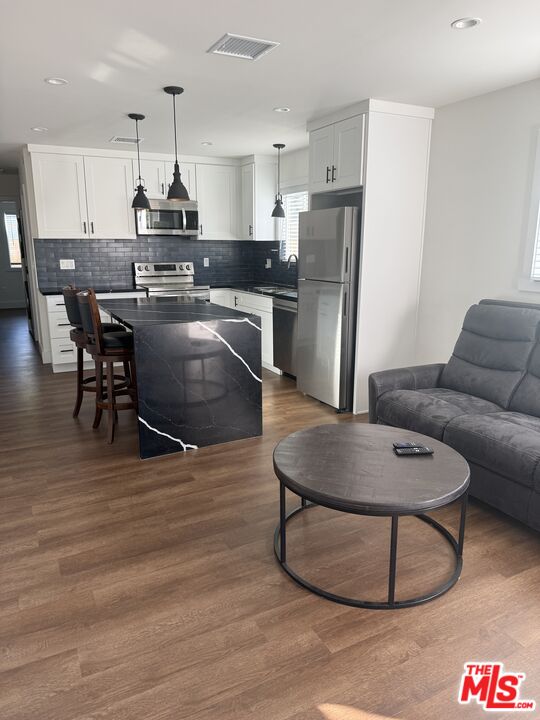 8302 Capps Avenue Northridge, CA 91324 - Photo 9 of 16 a kitchen with stainless steel appliances granite countertop a refrigerator a stove a sink a dining table and chairs with wooden floor
